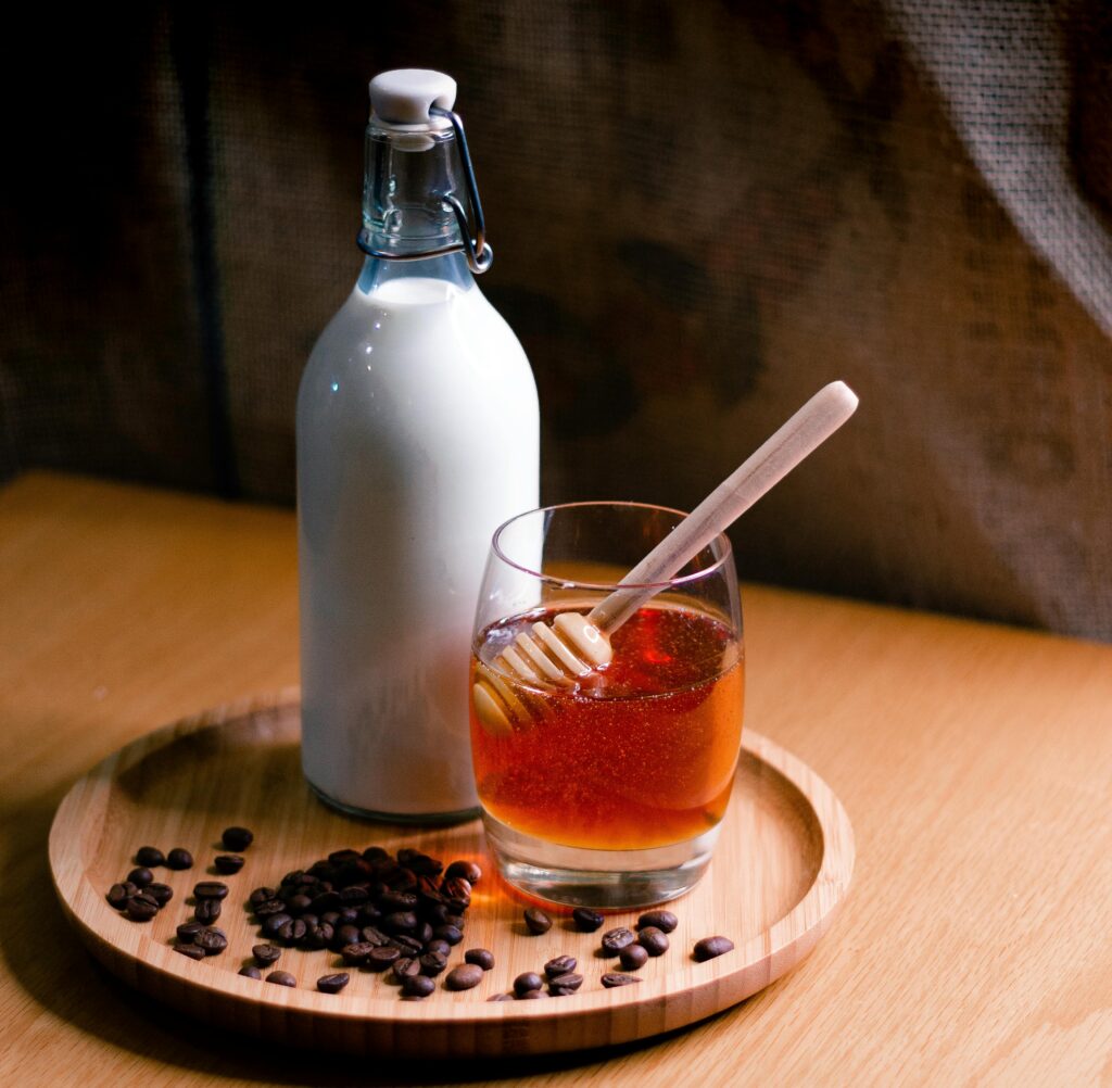 Elegant setup featuring a milk bottle and honey glass on a wooden tray with coffee beans.