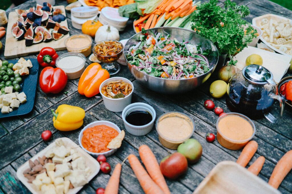 An inviting outdoor picnic spread with fresh vegetables, dips, and salads on a rustic table.